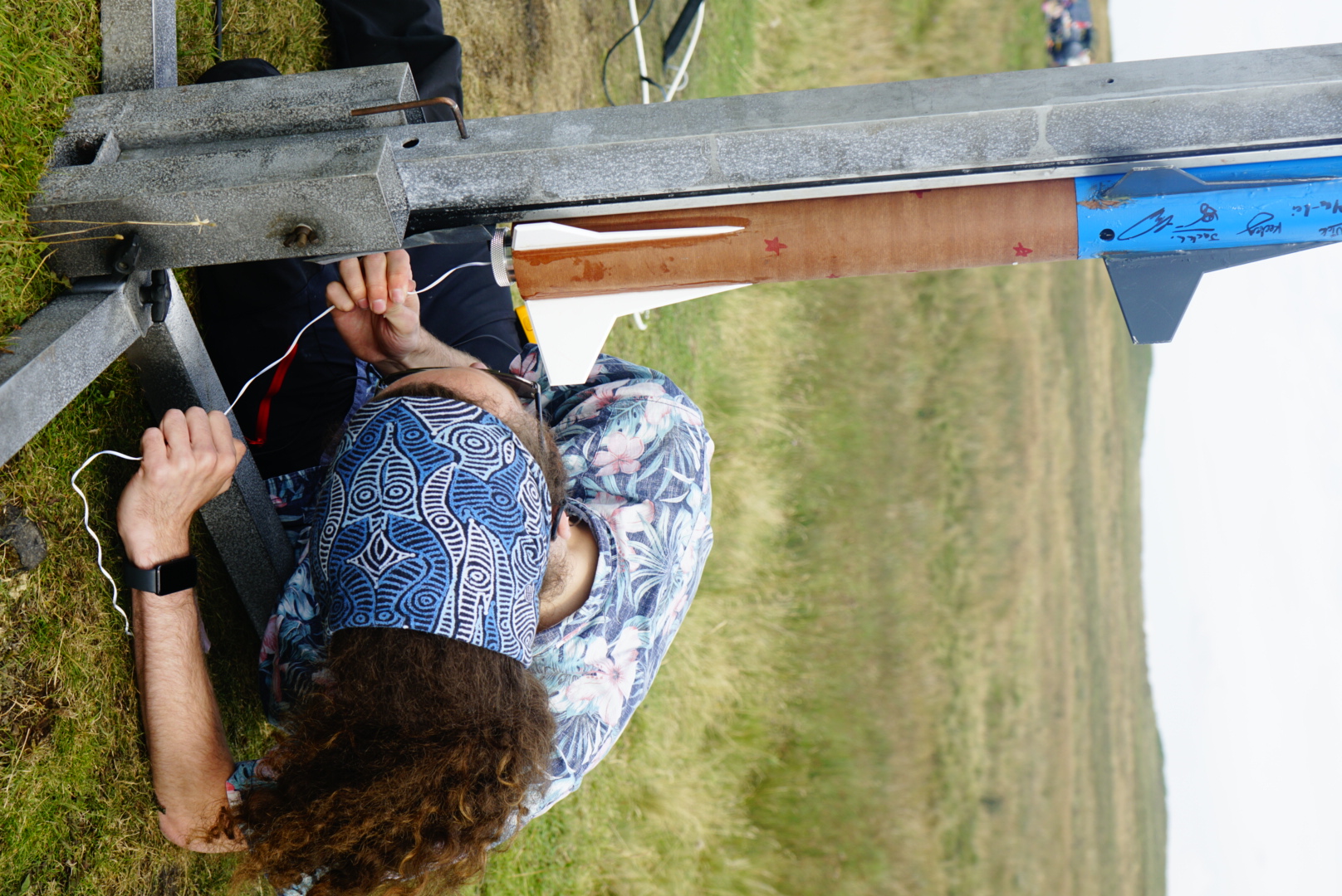 Two team members connecting wiring at the base of a launch rail