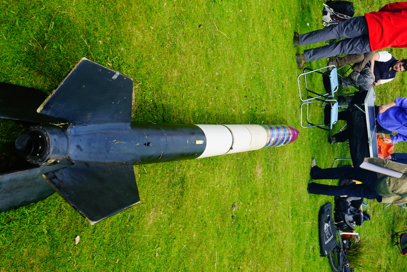 A large black and white rocket laid out on grass before launch